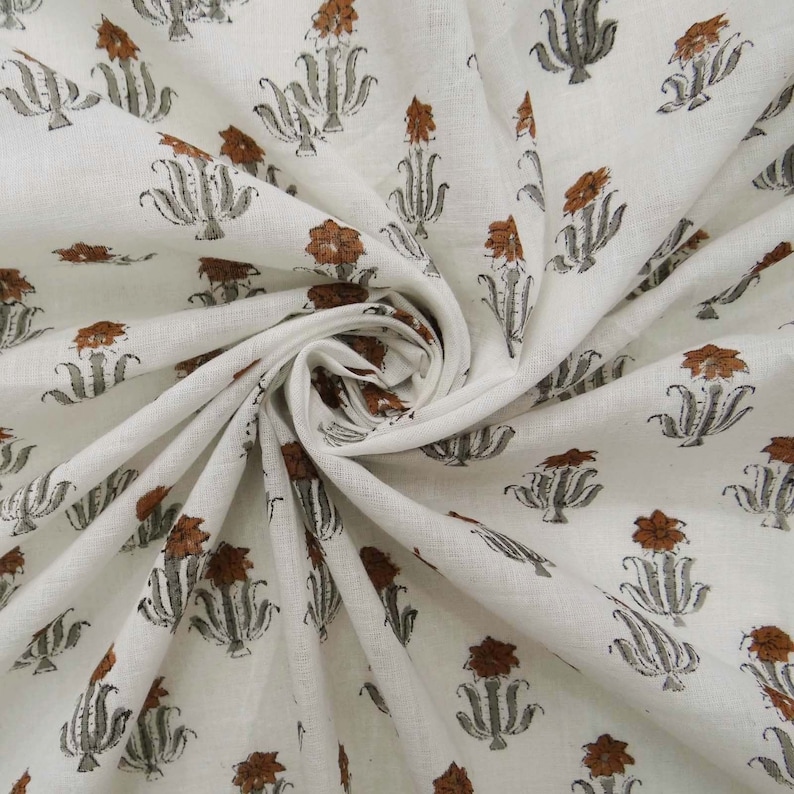 Grey White floral hand block print cotton fabric featuring traditional Indian artisan craftsmanship on soft lightweight cotton. This handmade Jaipur block printed fabric is shown in a swirl drape to highlight its smooth texture, natural flow, and elegant floral motif. Perfect for dressmaking, quilting, sewing, kurtas, summer dresses, blouses, home décor, DIY crafts, and fabric by the yard projects. 
 
block print fabric, fabric by the yards, cotton fabric, hand dyed fabric, Indian cotton fabric