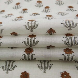 Grey White floral hand block print cotton fabric featuring traditional Indian artisan craftsmanship on soft lightweight cotton. This handmade Jaipur block printed fabric is shown in a swirl drape to highlight its smooth texture, natural flow, and elegant floral motif. Perfect for dressmaking, quilting, sewing, kurtas, summer dresses, blouses, home décor, DIY crafts, and fabric by the yard projects. 
 
block print fabric, fabric by the yards, cotton fabric, hand dyed fabric, Indian cotton fabric