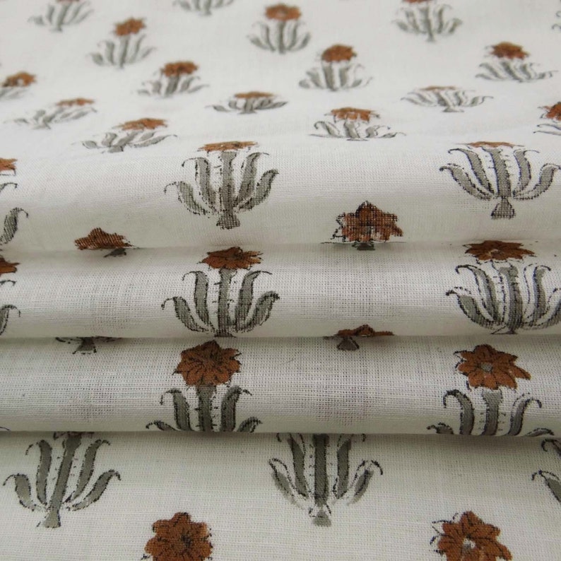 Grey White floral hand block print cotton fabric featuring traditional Indian artisan craftsmanship on soft lightweight cotton. This handmade Jaipur block printed fabric is shown in a swirl drape to highlight its smooth texture, natural flow, and elegant floral motif. Perfect for dressmaking, quilting, sewing, kurtas, summer dresses, blouses, home décor, DIY crafts, and fabric by the yard projects. 
 
block print fabric, fabric by the yards, cotton fabric, hand dyed fabric, Indian cotton fabric