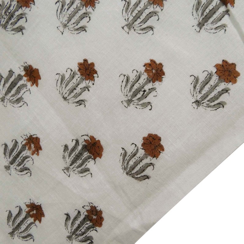 Grey White floral hand block print cotton fabric featuring traditional Indian artisan craftsmanship on soft lightweight cotton. This handmade Jaipur block printed fabric is shown in a swirl drape to highlight its smooth texture, natural flow, and elegant floral motif. Perfect for dressmaking, quilting, sewing, kurtas, summer dresses, blouses, home décor, DIY crafts, and fabric by the yard projects. 
 
block print fabric, fabric by the yards, cotton fabric, hand dyed fabric, Indian cotton fabric