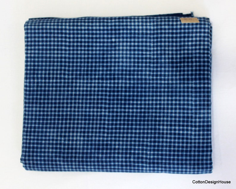 May include: A folded piece of blue and white gingham fabric. The fabric has a small checkered pattern.