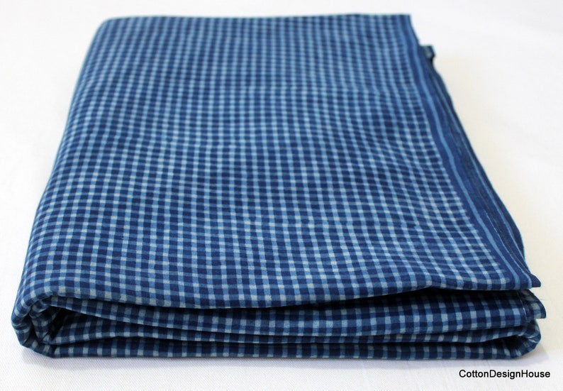 May include: A folded blue and white gingham fabric. The fabric has a checkered pattern.