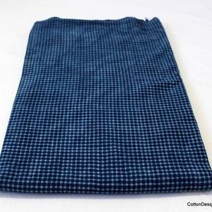May include: A folded piece of blue and white gingham fabric. The fabric has a small checkered pattern.