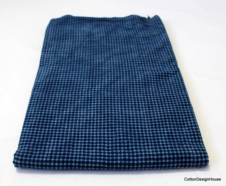 May include: A folded piece of blue and white gingham fabric. The fabric has a small checkered pattern.