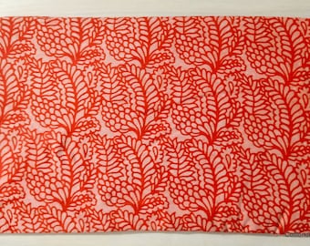 May include: Red and pink fabric with a floral pattern. The fabric has a repeating pattern of red leaves on a pink background.