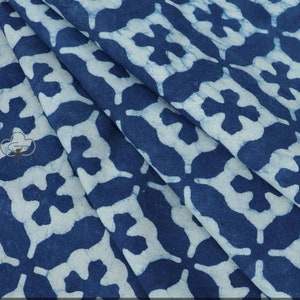 Puede incluir: Tela azul y blanca con un patrón repetitivo de flores estilizadas. La tela tiene un tacto suave y texturizado.