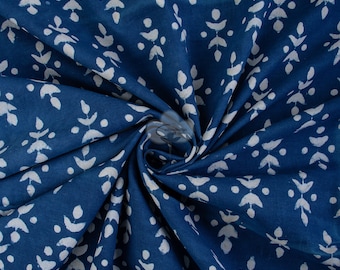 Pode incluir: Tecido de algodão azul-índigo com um padrão floral branco. O tecido está dobrado e drapeado, mostrando a textura e o design.