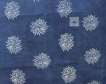 Pode incluir: Tecido azul índigo com um padrão branco repetitivo de formas de flores estilizadas.