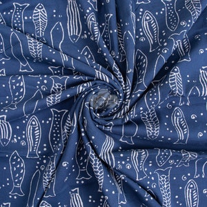 Peut inclure: Un tissu bleu avec un motif de poissons blancs. Le tissu est plié et tordu, créant un effet tourbillonnant.