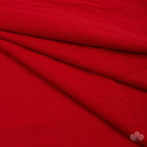 Puede incluir: Tela roja con una textura lisa y uniforme. La tela está doblada de una manera que muestra el drapeado y el flujo del material.