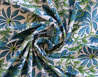 May include: White cotton fabric with a blue and green floral print. The fabric is folded and twisted, showing the pattern.
