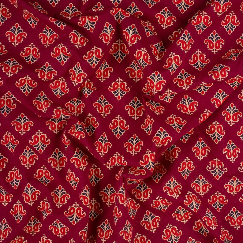 Hand block printed 100% cotton fabric featuring a traditional Indian floral pattern with intricate artisan detailing. Soft, breathable, lightweight fabric sold by the yard, ideal for sewing dresses, blouses, skirts, quilting, patchwork, home décor, cushion covers, curtains, table linens, tote bags, and a variety of DIY craft projects. Perfect for fashion designers, crafters, and handmade creations.
