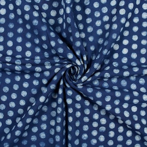May include: Blue fabric with a white polka dot pattern. The fabric is folded and twisted, showing the texture of the material.