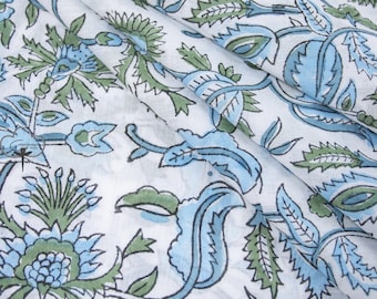 May include: White cotton fabric with a blue and green floral print. The fabric has a paisley-like design with intricate details.