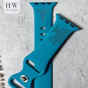 May include: Two turquoise watch bands with black engraved designs. One band features a caduceus symbol, and the other says "Doctor On Duty." The bands are made of a flexible material and have a metal clasp.