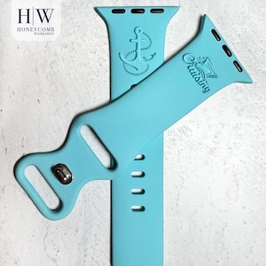 May include: Two light blue watch bands. One band features an anchor design, and the other has a ship with the word "Cruising". The bands are made of a flexible material and have a metal clasp.
