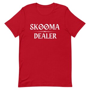 May include: Red t-shirt with white text that reads "SKOOMA DEALER" with a stylized design above the word "DEALER".