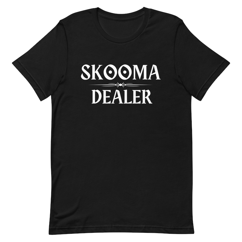 May include: Black t-shirt with white text that reads "SKOOMA DEALER" with a stylized symbol above the word "SKOOMA".