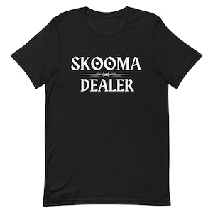 May include: Black t-shirt with white text that reads "SKOOMA DEALER" with a stylized design above the word "DEALER".