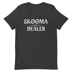 May include: Dark grey t-shirt with white text that reads "SKOOMA DEALER" with a stylized symbol above the word "SKOOMA".