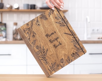 May include: A wooden recipe book with a floral design and the text "Mom's Recipe Book" engraved on the cover.