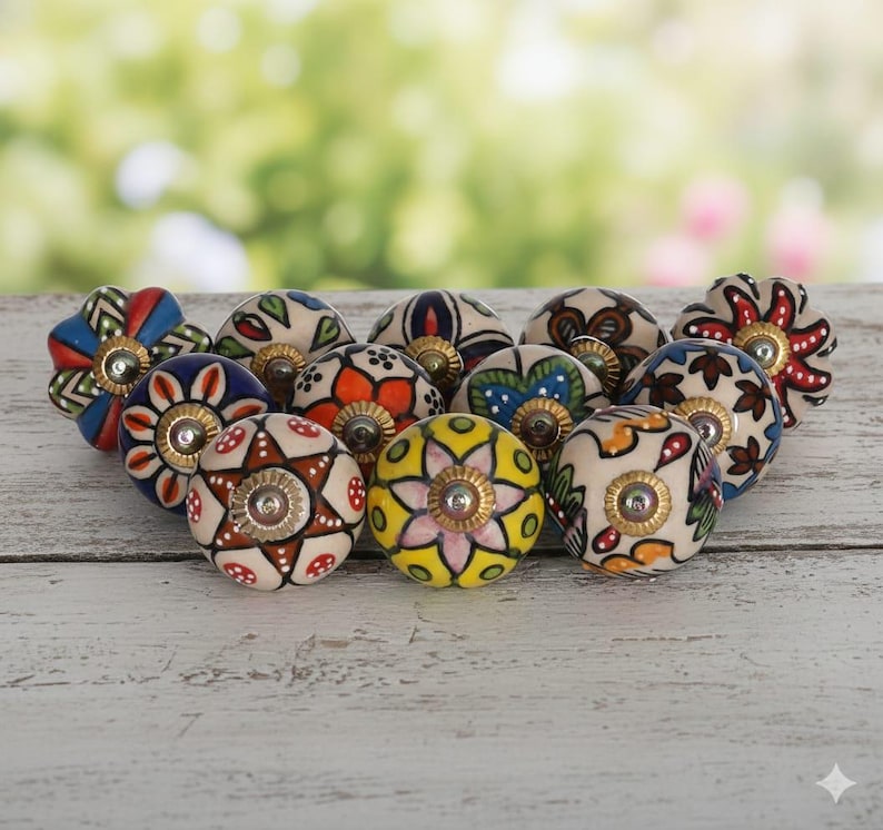 May include: A collection of twelve round ceramic cabinet knobs featuring various hand-painted floral and geometric patterns in vibrant colors including red, blue, yellow, green, and orange, each finished with a central metallic silver screw head.