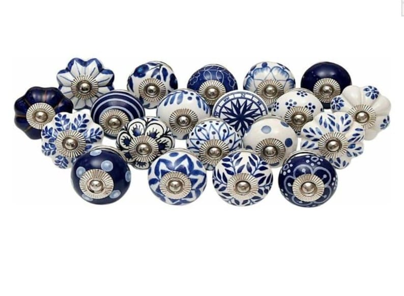 Op de afbeelding: Een verzameling van achttien ronde keramische kastknoppen met diverse blauw-witte patronen, waaronder bloemmotieven, geometrische vormen en strepen. Elke knop heeft een centraal zilverkleurig metalen onderdeel voor bevestiging.
