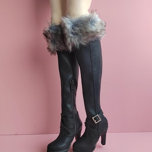 May include: Black leather thigh-high boots with a faux fur cuff and a silver buckle. The boots have a high heel and a zipper on the back.