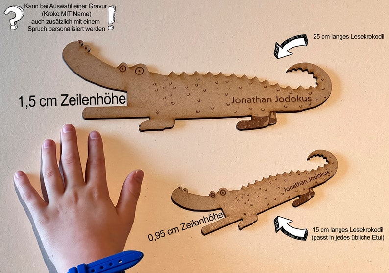 Może przedstawiać: Dwie drewniane zakładki w kształcie krokodyla. Większa ma 25 cm długości, a mniejsza 15 cm. Obie mają wygrawerowane imię "Jonathan Jodokus". Większa zakładka ma 1,5 cm wysokości, a mniejsza 0,95 cm.