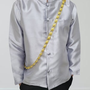 May include: A silver long-sleeved shirt with a mandarin collar and a gold chain with decorative links. The shirt has five buttons down the front.
