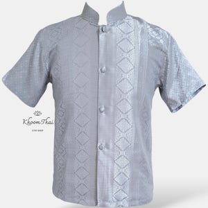 May include: A silver short-sleeved shirt with a mandarin collar and a button-up front. The shirt has a geometric pattern and a vertical stripe down the centre.