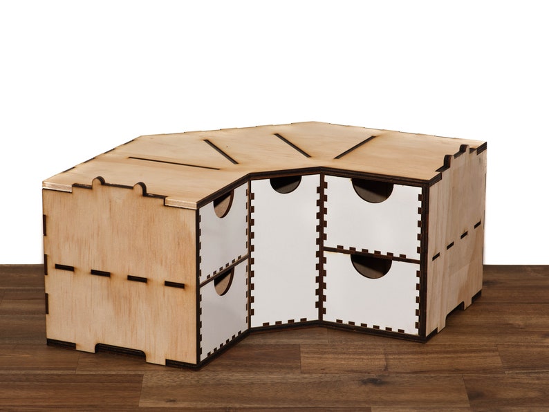 Puede incluir: Una estanter&iacute;a de esquina de madera con seis cajones. Los cajones son blancos con un borde negro. La estanter&iacute;a est&aacute; hecha de madera clara con un acabado natural.