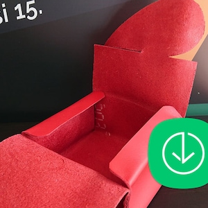 May include: A red leather box with a hinged lid. The box is open and empty.