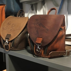 May include: Three small leather backpacks with different designs. The backpacks are brown and have a flap closure with a metal clasp. The backpacks have a small pocket on the front and a zippered pocket on the side. The backpacks have adjustable straps.