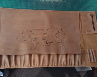 May include: A brown leather butcher block with a pig diagram showing different cuts of meat, including bacon, loin, leg ham, and shoulder. The block has multiple pockets and a zippered pouch.