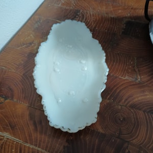 May include: White oval-shaped glass dish with a scalloped edge and a floral design in the center.