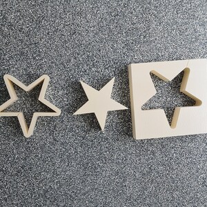 May include: Three wooden star-shaped cutouts. The largest cutout is a square with a star-shaped hole in the center. The other two cutouts are smaller and solid.
