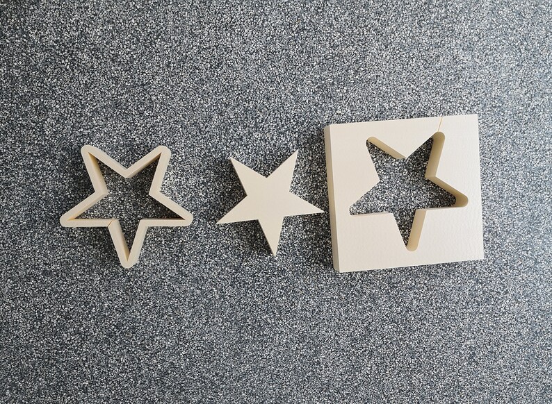 May include: Three wooden star-shaped cutouts. The largest cutout is a square with a star-shaped hole in the center. The other two cutouts are smaller and solid.