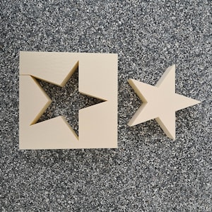 May include: Two beige foam stars, one with a star-shaped cutout, on a gray speckled surface.