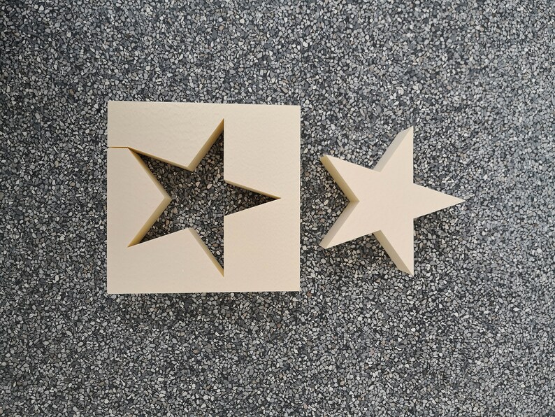 May include: Two beige foam stars, one with a star-shaped cutout, on a gray speckled surface.