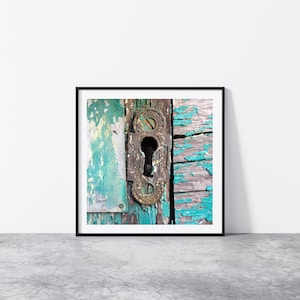 May include: A close-up of an old, weathered wooden door with peeling turquoise paint. A rusty metal keyhole is visible in the center of the door.