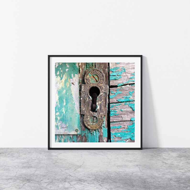 May include: A close-up of an old, weathered wooden door with peeling turquoise paint. A rusty metal keyhole is visible in the center of the door.