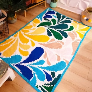 Peut inclure: Un tapis crocheté coloré avec un motif géométrique dans des tons de bleu, vert, jaune et rose. Le tapis a une bordure turquoise et est posé sur un sol en bois.