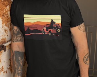 May include: A black t-shirt with a retro-style graphic of a red jeep driving through a desert landscape with a sunset in the background.