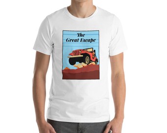 May include: White t-shirt featuring a graphic of a red jeep jumping over a brown hill, with the text "The Great Escape" in a blue rectangle. The jeep has black accents and is set against a blue sky.