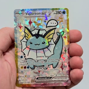 May include: A holographic Vaporeon EX Pokémon trading card. The card features a light blue Vaporeon character with black outlines and a speech bubble. The card has text that includes "Severe Squall" and "Aquamarine".