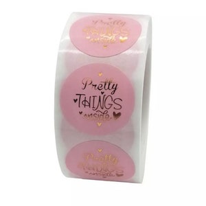 May include: Roll of pink round stickers with gold foil lettering that says "Pretty Things Inside" with a heart on each side of the text.