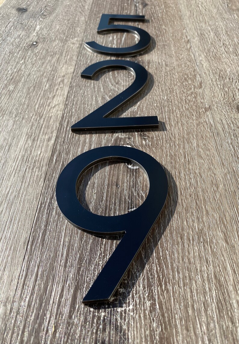 May include: Black metal house numbers 529, mounted on a wood surface.