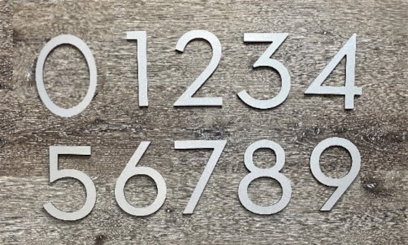 May include: Silver metal house numbers 0 through 9. The numbers are modern and minimalist in style.