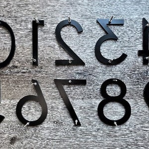 May include: Black metal house numbers 1 through 9, each number is attached to a wooden surface with screws.